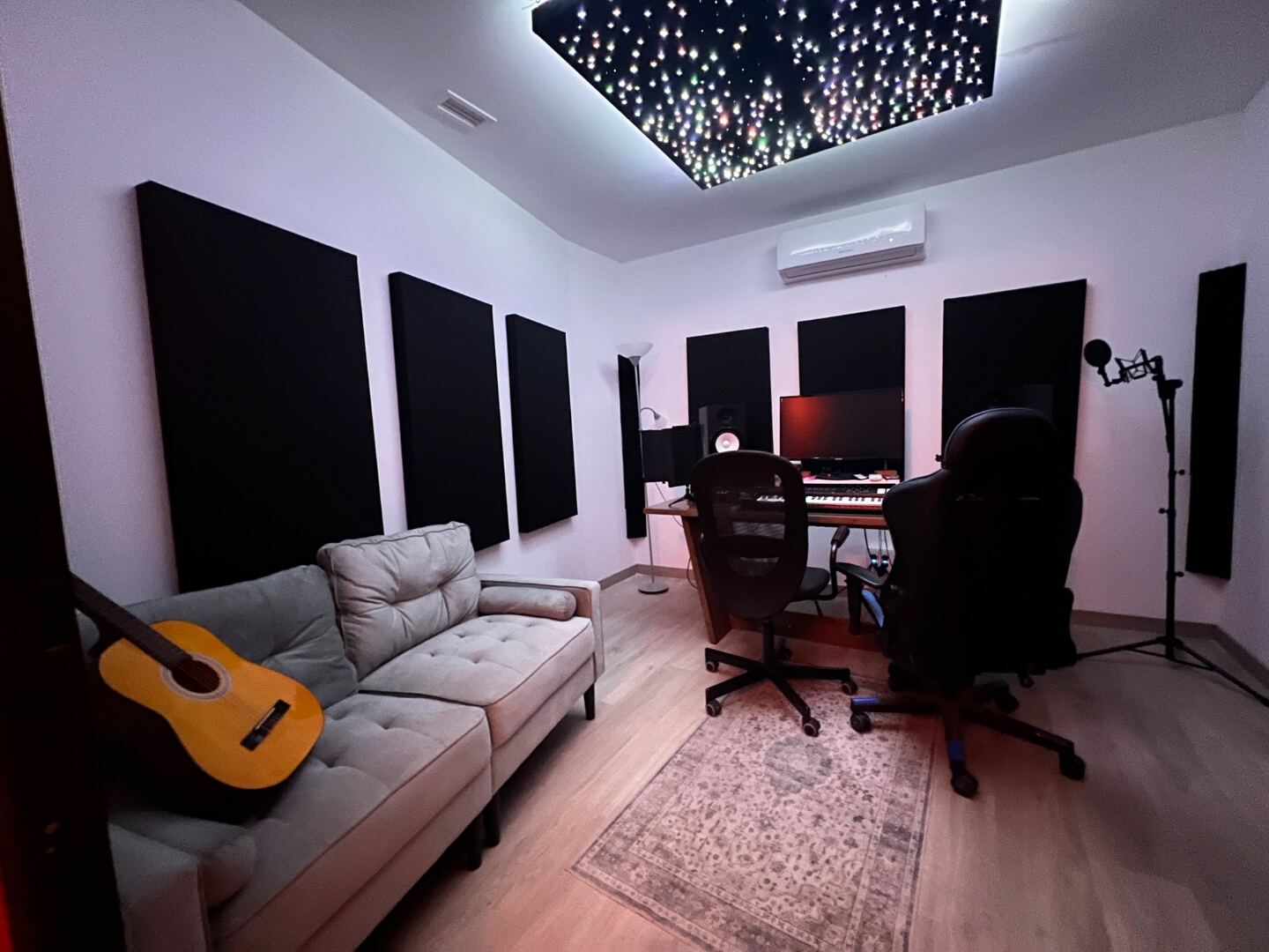 Estudio equipado con guitarra, sofá y mesa de producción